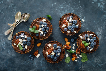 Healthy raw vegan dessert dates tartlets with chocolate cream of cashew, decorated with almond,...