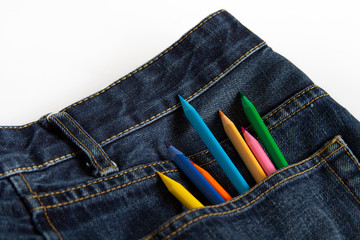 Color pencils stick out in blue jeans pocket on a white background.