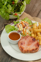 Grilled ham steak with barbecue sauce, side dish salad and french fries on sackcloth. Copy space