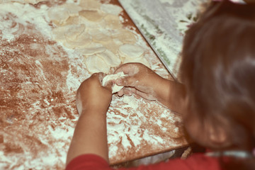Family concept. Cooking together with children. Little girl leaning how to make manti dumplings. Close up child hands