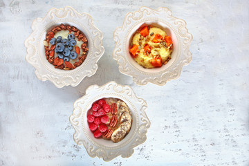Three different Breakfast cereals in white textured dishes. Copy of the space. Photo on a white textured background.