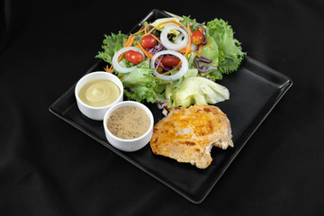 Grilled chicken breast salad with dressings and orange juice on black background  - Copy space