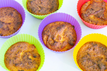 Homemade chocolate muffins in multi-colored silicone cups close-up on a white background