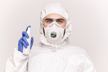 Handsome young man in protective workwear spraying sanitizer around himself