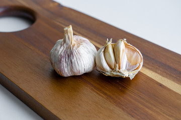 closeup macro view of two garlic heads which are laying on wooden cutting board at kitchen