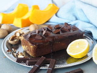 Festive homemade chocolate pumpkin long rectangular cupcake glazed with chocolate. Wooden table.