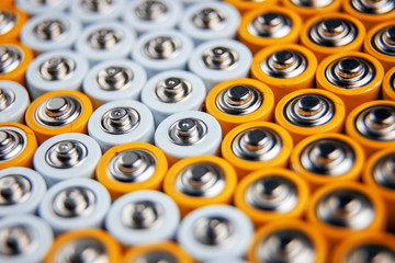 A large number of old AA batteries. The batteries are laid out in a square shape. Batteries form a beautiful background. A variety of power sources. Pattern of batteries laid out in a row.