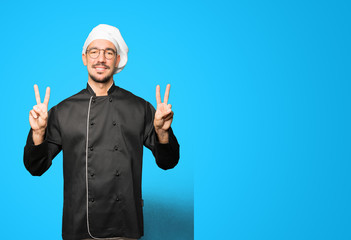 Happy young chef making a victory gesture with his fingers