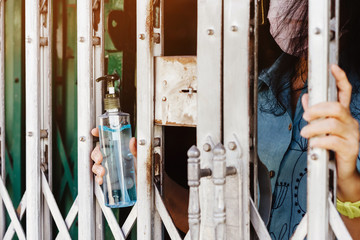 A woman wear surgical face mask and home quarantine herself in house by giving alcohol gel to clean germs to people who deliver food. Physical distancing for protect Covid-19 concept.