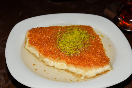Turkish dessert kunefe with pistachio powder. Kunafa, kadayif with pistachio powder and cheese hot