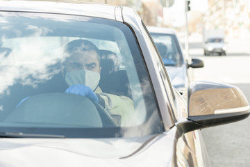 Young man in mask and gloves driving to clients while delivering ordered goods