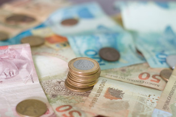 several Brazilian currency notes, BRL, with focus on 1 real coin stack