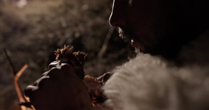 Primitive man eating meat near fire