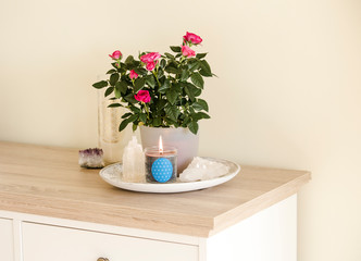 Burning glass candle with homemade sign showing Flower of Life symbol in home interior with semi precious stone geodes. Spiritual symbols in home decor concept.