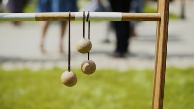 Wooden ladder golf balls hang on a wooden bar on a sunny day, people stand in the background