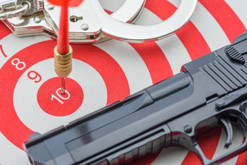 Red dart hits in the center number 10 of a target with a pair of handcuff and a pistal