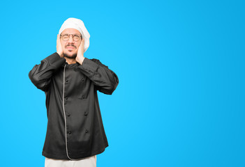 Concerned young chef worried about loud noises and covering his ears