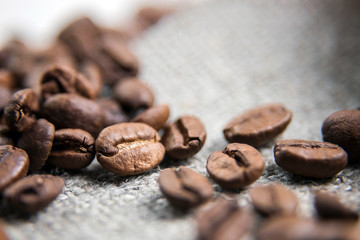 Brown coffee bean close-up.The grains lie on a sacking with a beautiful texture. Macrophotography of coffee. Beautiful grains.