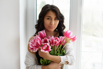 A portrait of beautiful young woman with pink tulips.