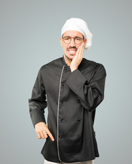 Concerned young chef with a toothache gesture