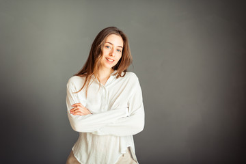 Young girl in a white shirt, hands up, on a gray background. Honest and emotional on the banner, billboard, billboard. No retouch. Without make-up.