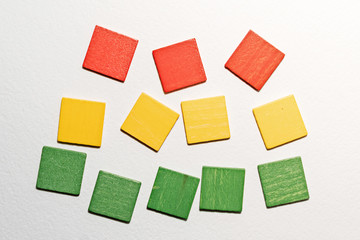 Different colorful squares wooden on white background. Geometric shapes red, green, yellow colors, top view. Concept of geometry. Copy space. Children educational logical task. Flat lay.