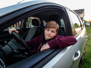 Eleven-year-old Caucasian boy sits in the driver's seat