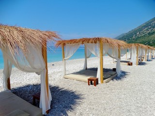 Imagen de las solitarias camas con techo sobre la arena blanca de la playa de Plazhi i Palasës en...