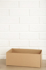 Cardboard box on white brick wall background. Copy space