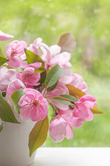 Naklejka na ściany i meble Pink flowers of decorative apple tree in a small white vase on a windowsill. Image for design postcards, calendar, book cover. selective focus.