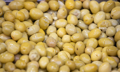 Pickled green olives were photographed on the counter in front of the market. Close up.
