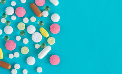 Many pills are poured from a medicine bottle. Pills and pills on a blue background. Medical tablets: analgesics, antipyretics.