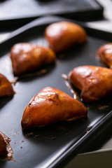 Shiny golden pies in triangle shape on pan