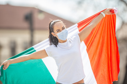 Female In Face Mask Holds Italian Flag On A Street Celebrating Lifting The Restrictions Implemented Due To A Coronavirus