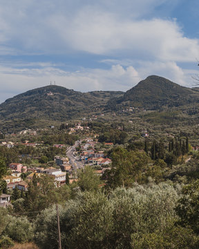 Moraitika, Corfu. Mediterranean town with forests around and hills in the background. Cloudy skies.