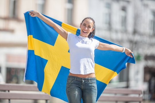 Fan of Sweden cheers for winning holding a flag on a sunny day outdoors