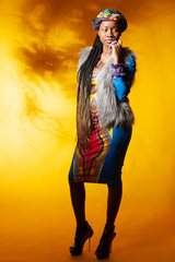 Black model. The girl is dressed in African style. African fashion. The woman is thinking. Black woman misses loved ones. Girl reflects on the future. African american on a yellow background.