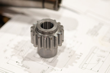 The gear lies on the drawing, advertising the production of mechanical engineering, gear-cutting...
