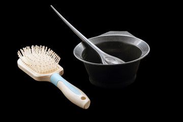Mixing hair dye in a special plastic bowl, hair brush with a white handle. Concept is hair coloring. Isolated on black. Professional hairdresser tools., close-up