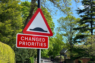 Changed Priorities Road sign. Change ahead, new normal. British Road sign on tree lined street in...