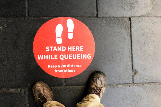 Floor Sign To Queue For Grocery Store Shopping. Keep Two Meters Apart To Stop The Spread Of Coronavirus Covid 19 By Social Distancing. The New Normal.