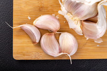 Peeled garlic cloves on a wooden board. Natural methods to prevent colds.