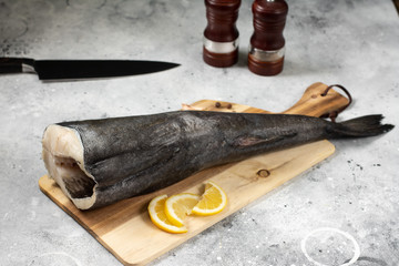 Black cod on a wooden Board on the light gray kitchen table. Top view with space for text