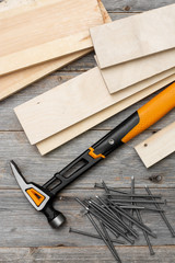 Carpentry tools hammer, nails, wooden bars, helmet and gloves on a gray wooden table