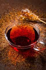 Cup of delicious rooibos tea on dark background