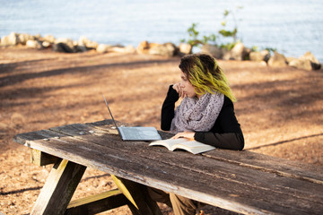 business woman working outdoors with computer on wooden table