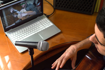 Young man recording himself while playing guitar and singing to share the video in social media. Musician recording a music video at home.