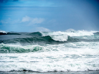 Big waves on the north shore of Oahu with aquamarine seas, white foam and blue skies.