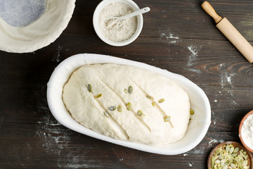 Homemade freshly prepared raw bread with pumpkin seed in a basket on a wooden dark background.