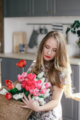 Blonde girl with a basket of tulips in the kitchen